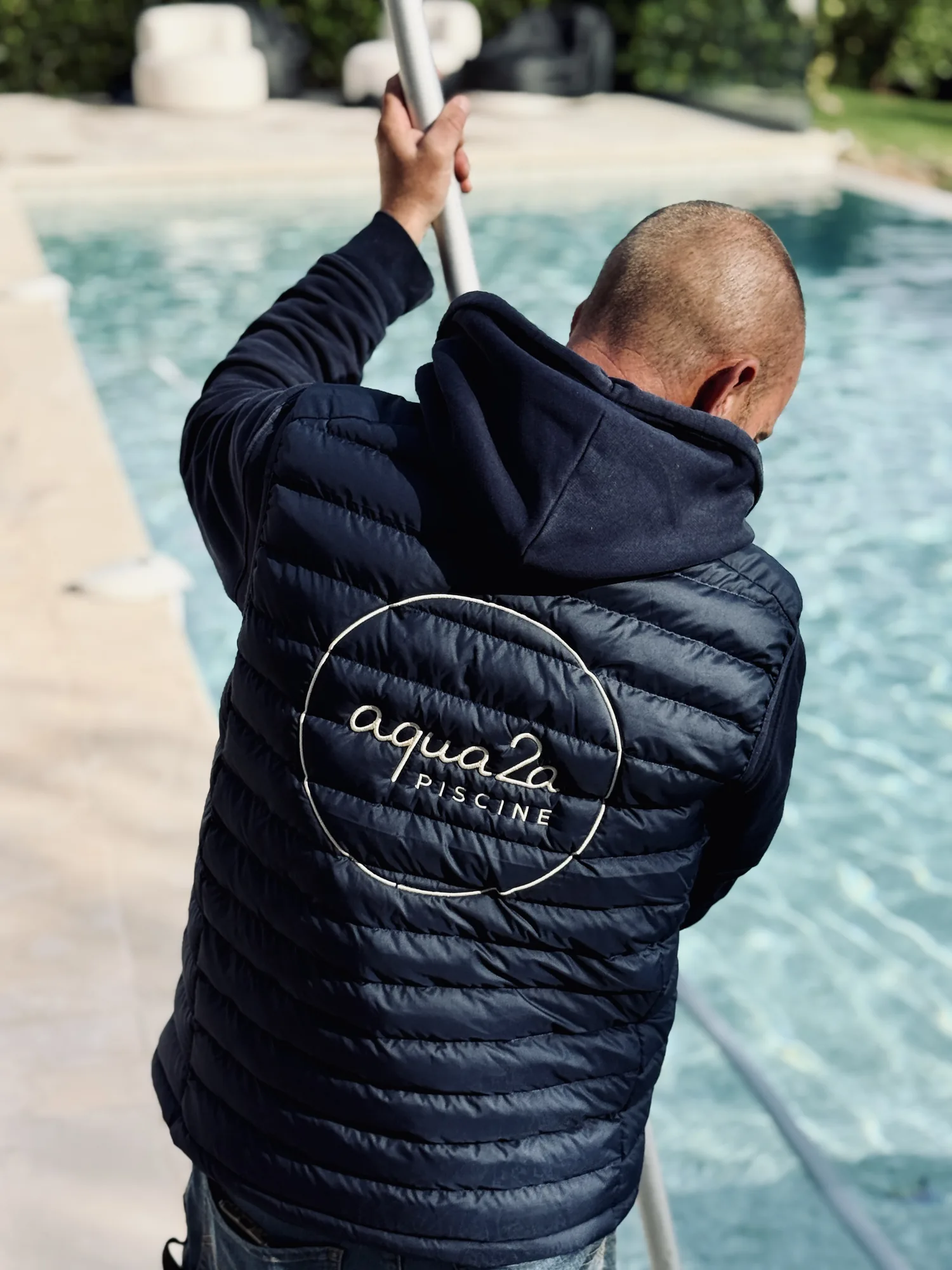 Technicien Aqua2A nettoyant une piscine à l’épuisette